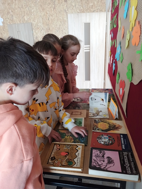 Uczniowie oglądają różne książki wyłożone na stoliku. Akcję „Książka szuka domu” przeprowadzają panie z biblioteki i cieszy się ona dużym zainteresowaniem.