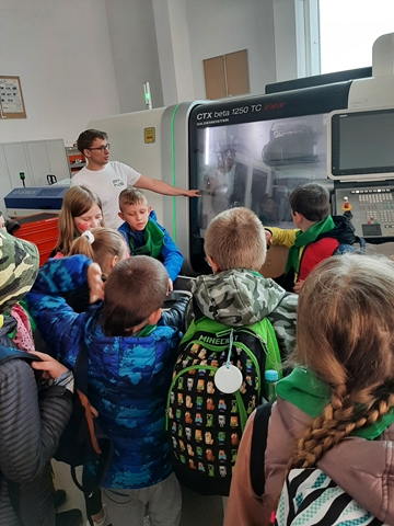 Na zdjęciu widać uczniów oraz prowadzącego warsztaty z okazji Dnia Młodego Naukowca. W tle widnieje sprzęt laboratoryjny.