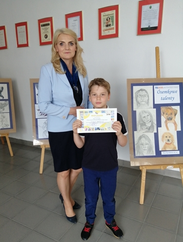 Zdjęcie przedstawia Panią Dyrektor oraz laureata Międzynarodowego Konkursu Plastycznego. Uczeń trzyma w rękach dyplom. 