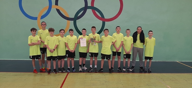 Zdjęcie drużyny chłopców. Zawodnicy w sportowych strojach prezentują puchar oraz dyplom.