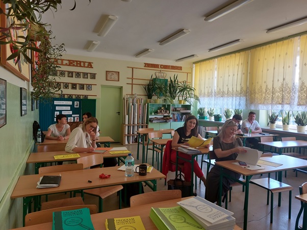Zdjęcie przedstawia grupę nauczycieli siedzących w ławkach, uczestniczących w szkoleniu dla realizatorów Programu Domowych Detektywów „Jaś i Małgosia na tropie”.