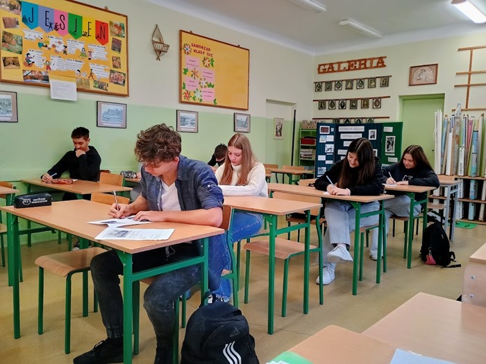 Zdjęcie przedstawia uczniów podczas rozwiązywania testu w historycznym konkursie międzyklasowym pod hasłem “Odrodzenie Państwa Polskiego”.
